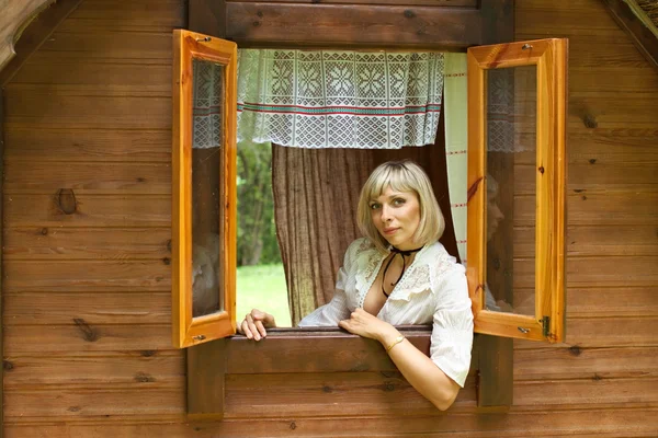 Menina europeia bonita olha pela janela — Fotografia de Stock