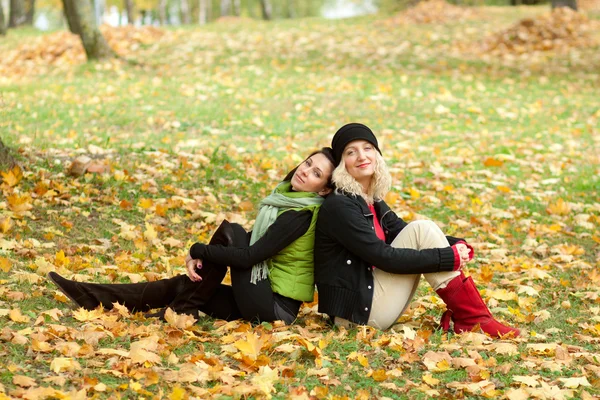 Due giovani donne sedute nel parco autunnale — Foto Stock