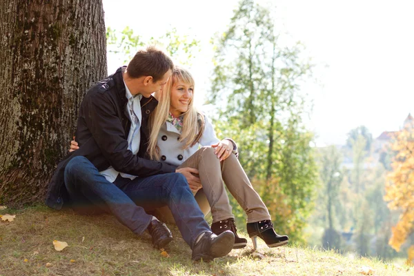Jeune couple amoureux assis sur le sol par arbre — Photo