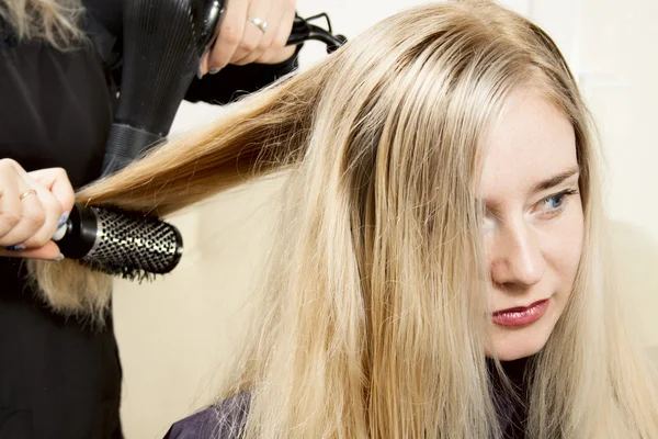 Cabeleireiros mãos secagem longo cabelo loiro — Fotografia de Stock