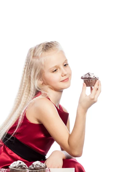 Mädchen hält einen Kuchen und schaut in die Kamera — Stockfoto