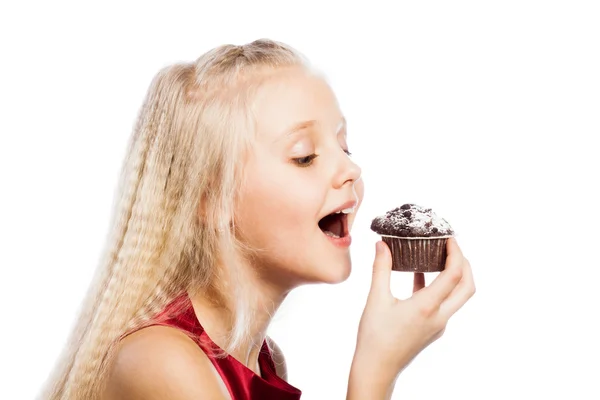 Mädchen beißt in einen Schokoladenkuchen — Stockfoto