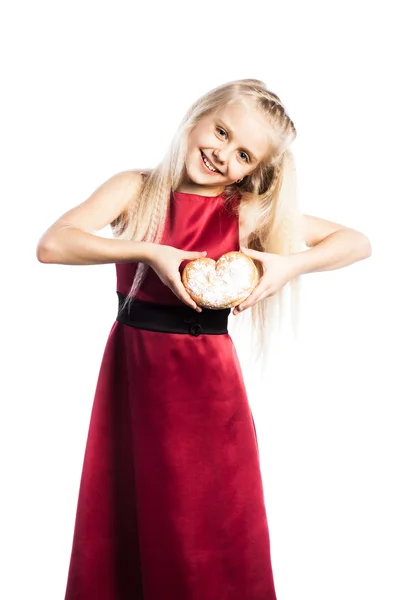 Chica sosteniendo una galleta en forma de corazón — Foto de Stock