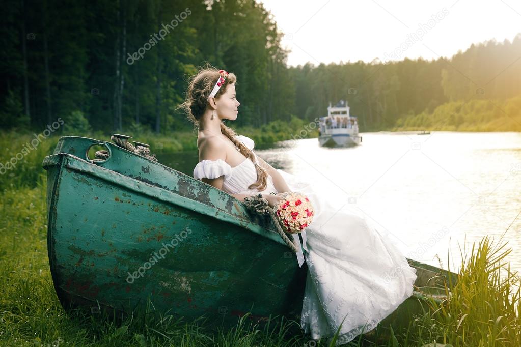 Beautiful young bride sitting on boat