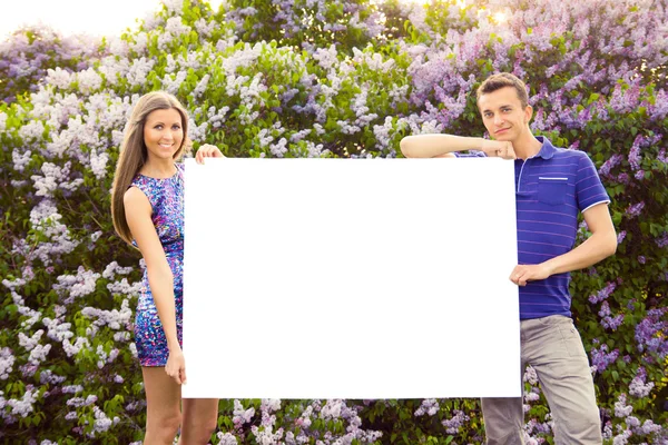 Casal jovem segurando cartaz em branco — Fotografia de Stock