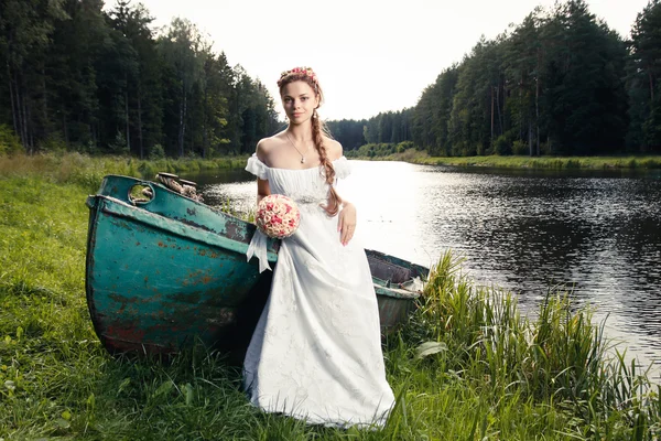 Bella giovane sposa seduta su barca — Foto Stock