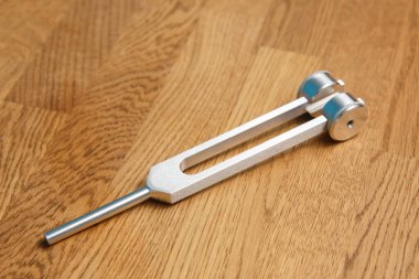 Ahşap bir arka planda metal bir diyapazon var. Müzik enstrümanlarını ayarlamak, ses terapisi veya rahatlamak için kullanılır..