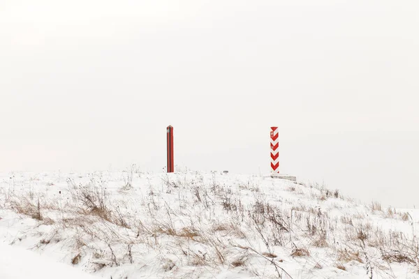 Boundary pillars of Belarus and Poland on the border in a winter field
