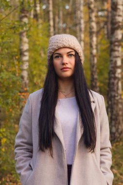 Sonbahar parkında eğlenen neşeli genç bir kadının portresi. Güz gri ceketli ve örgü şapkalı güzel esmer kız. Doğada rahatla..