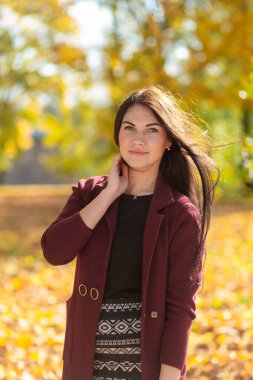 Sonbahar parkında eğlenen neşeli genç bir kadının portresi. Sonbahar kırmızı ceketli ve siyah kazaklı güzel esmer kız. Doğada rahatla. Yüksek kalite fotoğraf