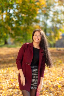 Sonbahar parkında eğlenen neşeli genç bir kadının portresi. Sonbahar kırmızı ceketli ve siyah kazaklı güzel esmer kız. Doğada rahatla. Yüksek kalite fotoğraf