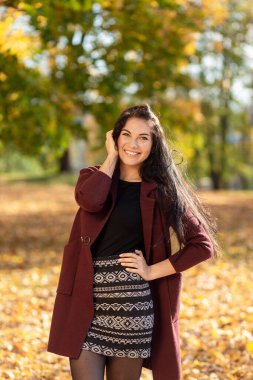 Sonbahar parkında eğlenen neşeli genç bir kadının portresi. Sonbahar kırmızı ceketli ve siyah kazaklı güzel esmer kız. Doğada rahatla. Yüksek kalite fotoğraf