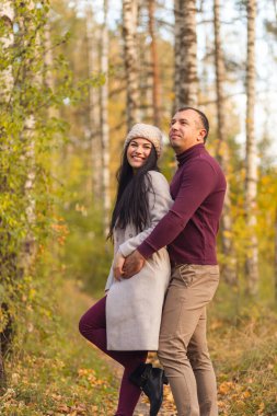 Doğada birlikte eğlenen sevimli bir çift. Genç bir adam ve bir kadın, altın sonbaharda huş ağacında sarılıp poz verirler. Tatiller, aşk, seyahat, turizm, ilişki ve flört kavramı.