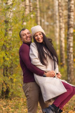 Doğada birlikte eğlenen sevimli bir çift. Genç bir adam ve bir kadın, altın sonbaharda huş ağacında sarılıp poz verirler. Tatiller, aşk, seyahat, turizm, ilişki ve flört kavramı.