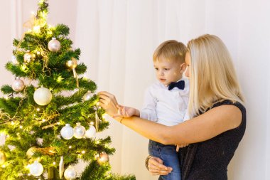 Anne ve oğul Noel ağacını altın toplar ve oyuncaklarla süslüyorlar. Aileyle Noel.