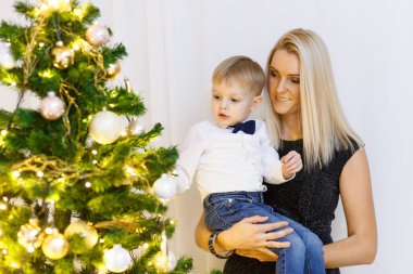 Anne ve oğul Noel ağacını altın toplar ve oyuncaklarla süslüyorlar. Aileyle Noel.
