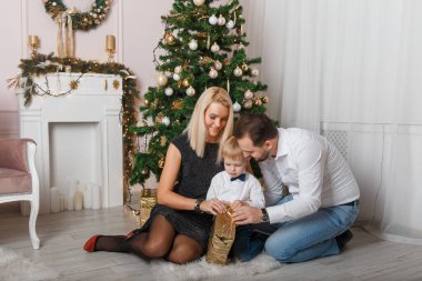 Mutlu, genç bir aile Noel 'i evde kutluyor. Küçük bir çocuk altın bir kutuda bir hediye aldı..