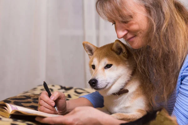 Yatağa Uzanmış Arkadaşı Shiba Inu Köpeğiyle Günlük Yazan Bir Kadın — Stok fotoğraf
