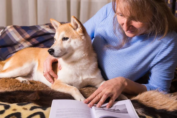 Yatağa Uzanmış Arkadaşı Shiba Inu Ile Kitap Okuyan Bir Kadın — Stok fotoğraf