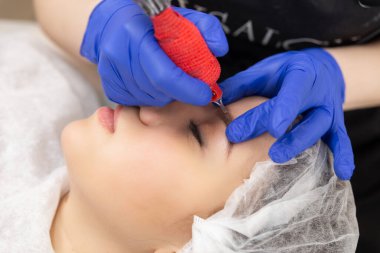 Kozmetik uzmanı, kaş dövmesine kalıcı makyaj uyguluyor. Kalıcı kaş makyajı prosedürü..