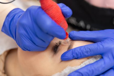 Kozmetik uzmanı, kaş dövmesine kalıcı makyaj uyguluyor. Kalıcı kaş makyajı prosedürü..