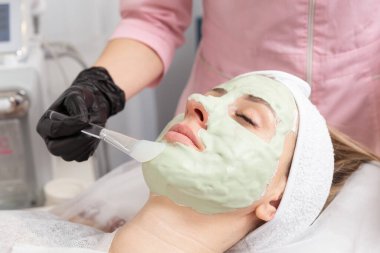 Açık yeşil yüz maskesi, spa tedavisi alternatif tıbbında fırçayla uygulanacak. Yüz soyma maskesi, kaplıca güzellik tedavisi, cilt bakımı.