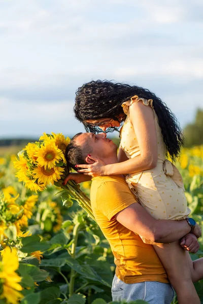 一对年轻漂亮的夫妇 一男一女 日落时分 拥抱在一片向日葵的田野里 家庭暑假的概念 一个浪漫的摄影 — 图库照片