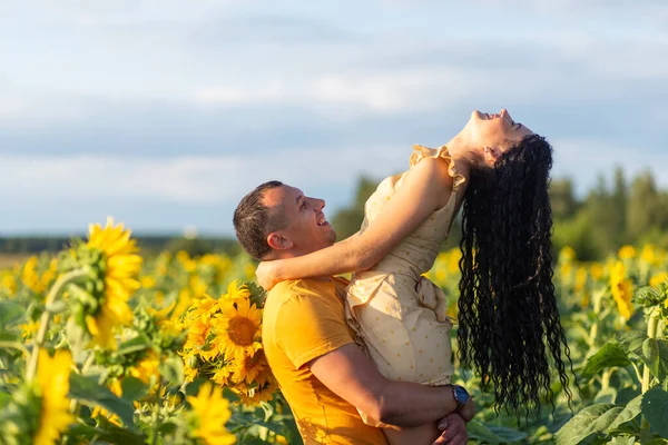 一对年轻漂亮的夫妇 一男一女 日落时分 拥抱在一片向日葵的田野里 家庭暑假的概念 一个浪漫的摄影 — 图库照片