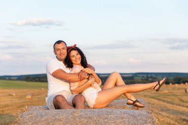 Tarlada saman rulolarının üzerinde birbirini seven bir çift. Genç adam ve kadın gün batımında eğleniyor, sarılıyor ve öpüşüyorlar..