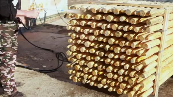 Arbetaren bearbetar träprodukter med en skyddande antiseptisk och svampdödande sammansättning Videoklipp