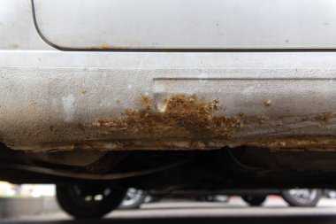 Beyaz eski arabanın yan tarafında pas var. Eski, yıpranmış metal yüzeydeki pas deliği..