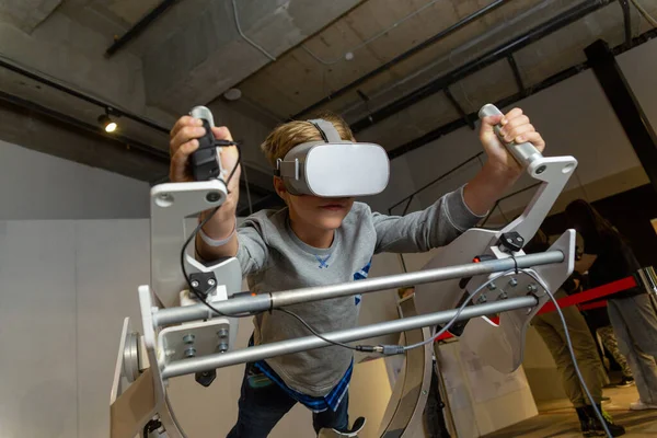 Young man playing virtual reality fly simulator at technology exhibition. Future and video game concept