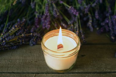 Ahşap fitili olan yanan mum ve arka planda lavanta