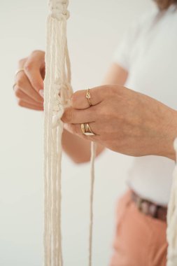 Kadınların elleri boho tarzında makrome desenli bir saksı dokuyor.. 