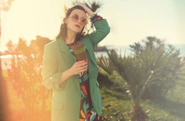 Dışarıda elinde bambu kahve fincanı tutan bir kadın var.