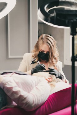 Kozmetik uzmanı bir müşteri için kalıcı makyaj kaşları uyguluyor.