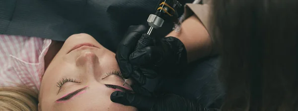Cosmetoloog aanbrengen van permanente make-up wenkbrauwen voor een klant — Stockfoto