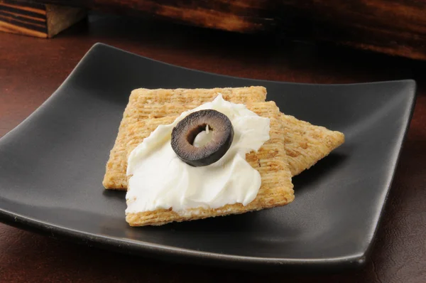 Wheat crackers with cream cheese and black olives — Stock Photo, Image