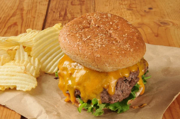 Cheesburger and potato chips on butcher paper — Stock Photo, Image