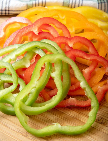 Pimientos Rojos Verdes Amarillos Anaranjados Rodajas Una Tabla Cortar Madera —  Fotos de Stock