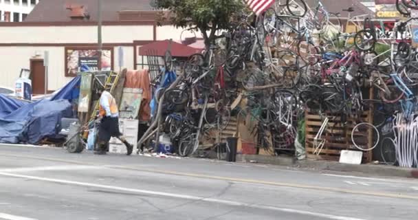 2021年10月1日 美国加利福尼亚州洛杉矶 人们在一座无家可归者营地的人行道上走过堆积如山的垃圾自行车 — 图库视频影像