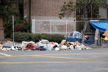 Los Angeles, CA USA - 28 Eylül 2021: Evsiz kampı ve şehirdeki bir apartmanın yanındaki çöp yığınları