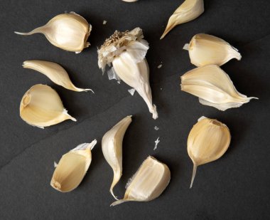 Koyu taş tezgahta taze organik sarımsak karanfilleri.