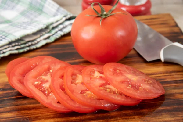 キッチンナイフで木製のまな板の上にジューシーな熟したトマトをスライス — ストック写真