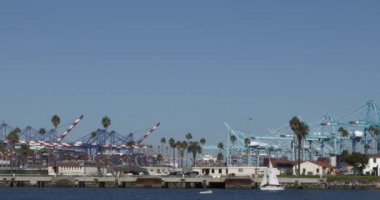 Los Angeles limanındaki vinçleri geçen yelkenliler.