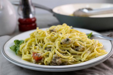 İstiridye soslu gurme linguine tabağı arka plandaki servis tavasına yakın.