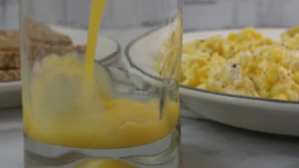 Verter Jugo Naranja Vaso Por Plato Huevos Revueltos — Vídeo de stock