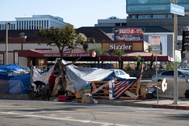 Los Angeles, CA USA - 14 Kasım 2021: Sizzler restoranının önündeki evsiz kampı ve Şükran Günü özel yemek afişi