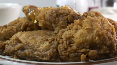 Ekmekli kızarmış tavuğun üzerine bal serpiştiriyorum. Yakın plan.