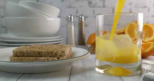Versare Succo Arancia Fresco Bicchiere Con Piatto Pane Caldo Imburrato — Video Stock